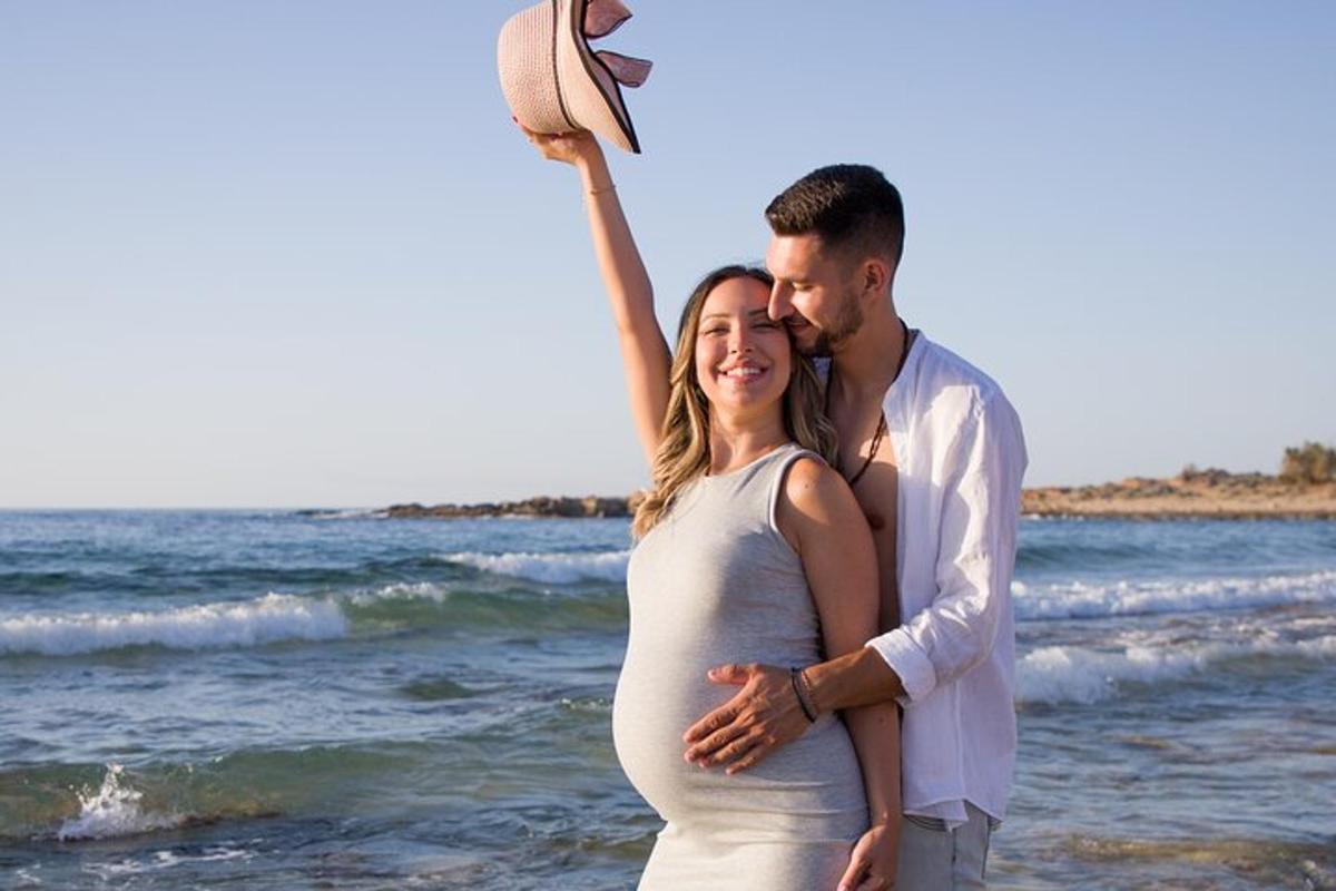un uomo e una donna incinta in piedi sulla spiaggia