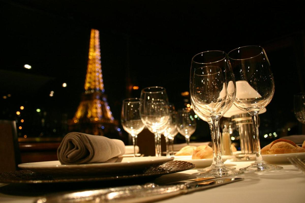 isang mesa na may mga baso ng alak at ang eiffel tower