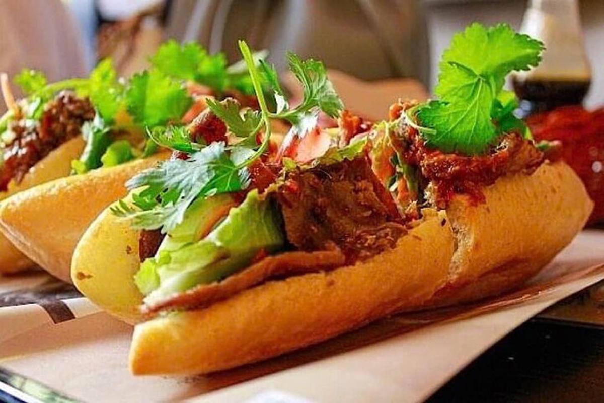 Un grupo de tres perritos calientes con lechuga y carne.