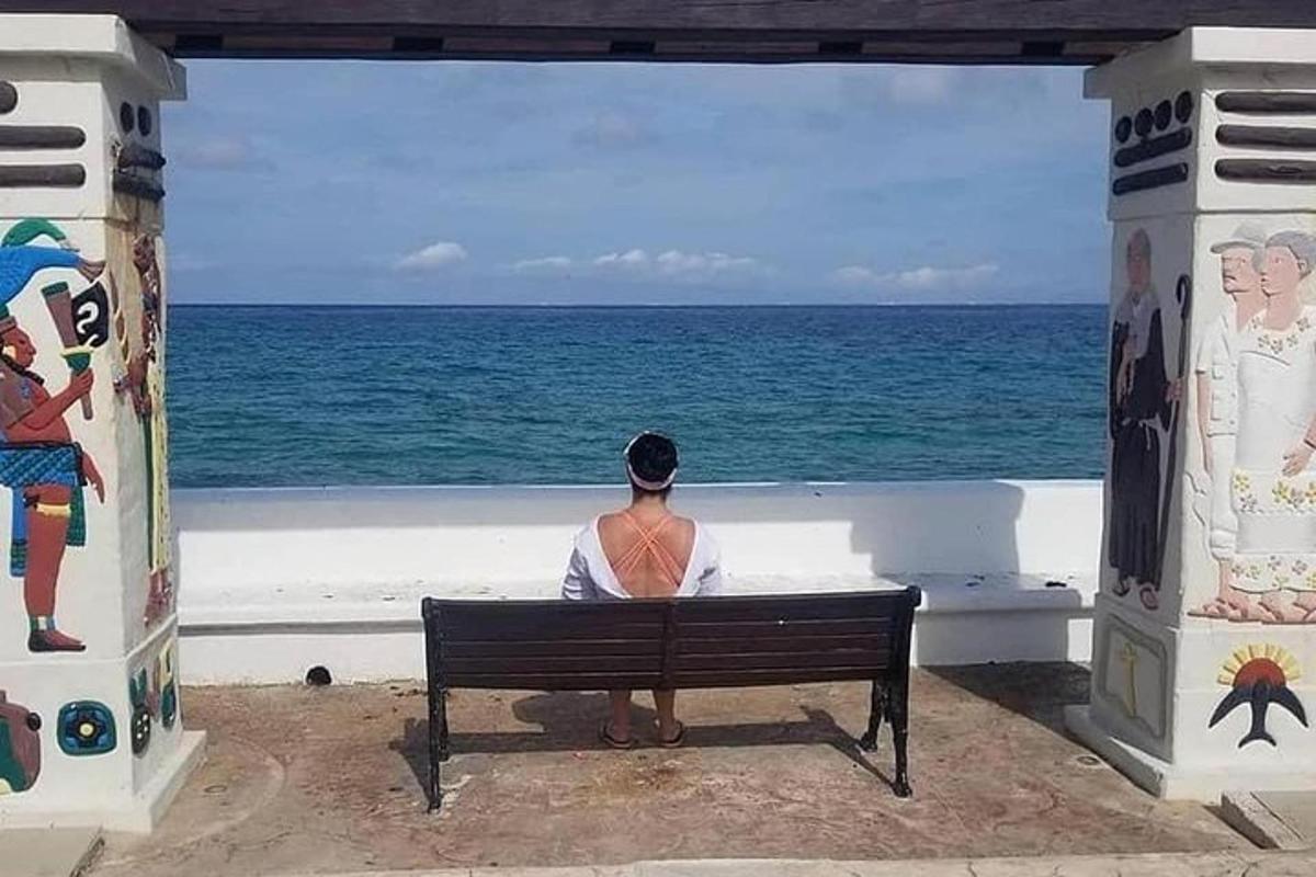 seorang lelaki duduk di atas bangku sambil memandang ke lautan