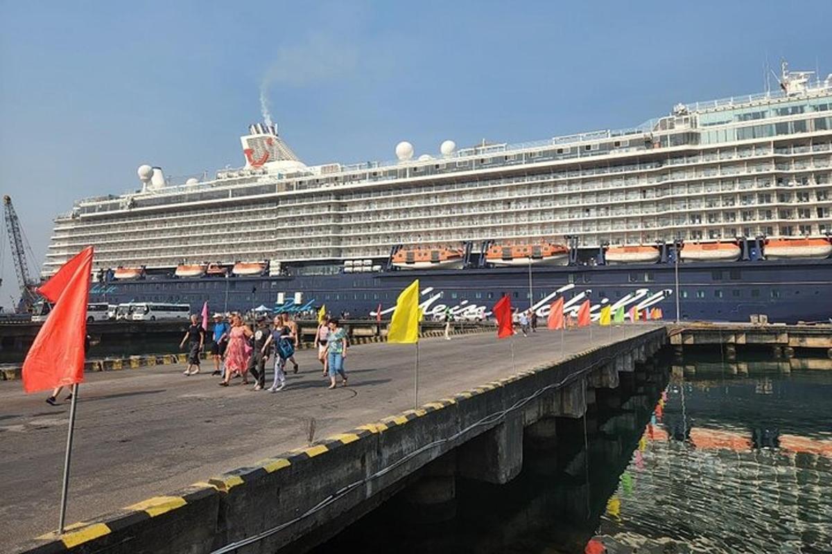 eine Gruppe von Menschen, die mit einem Kreuzfahrtschiff auf einem Pier spazieren gehen