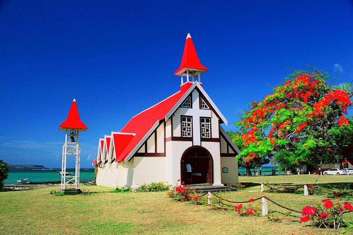 een klein kerkje met een rood dak en een toren