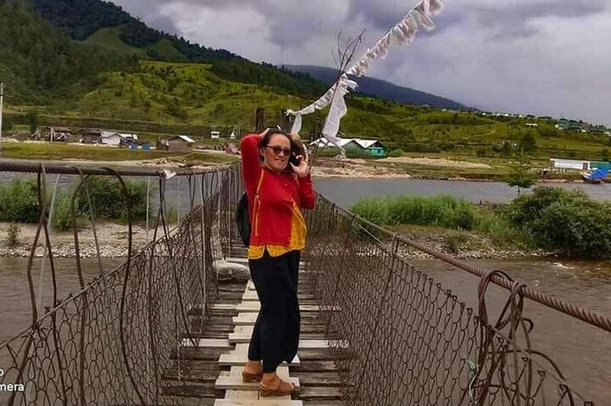 a woman is standing on a suspension bridge