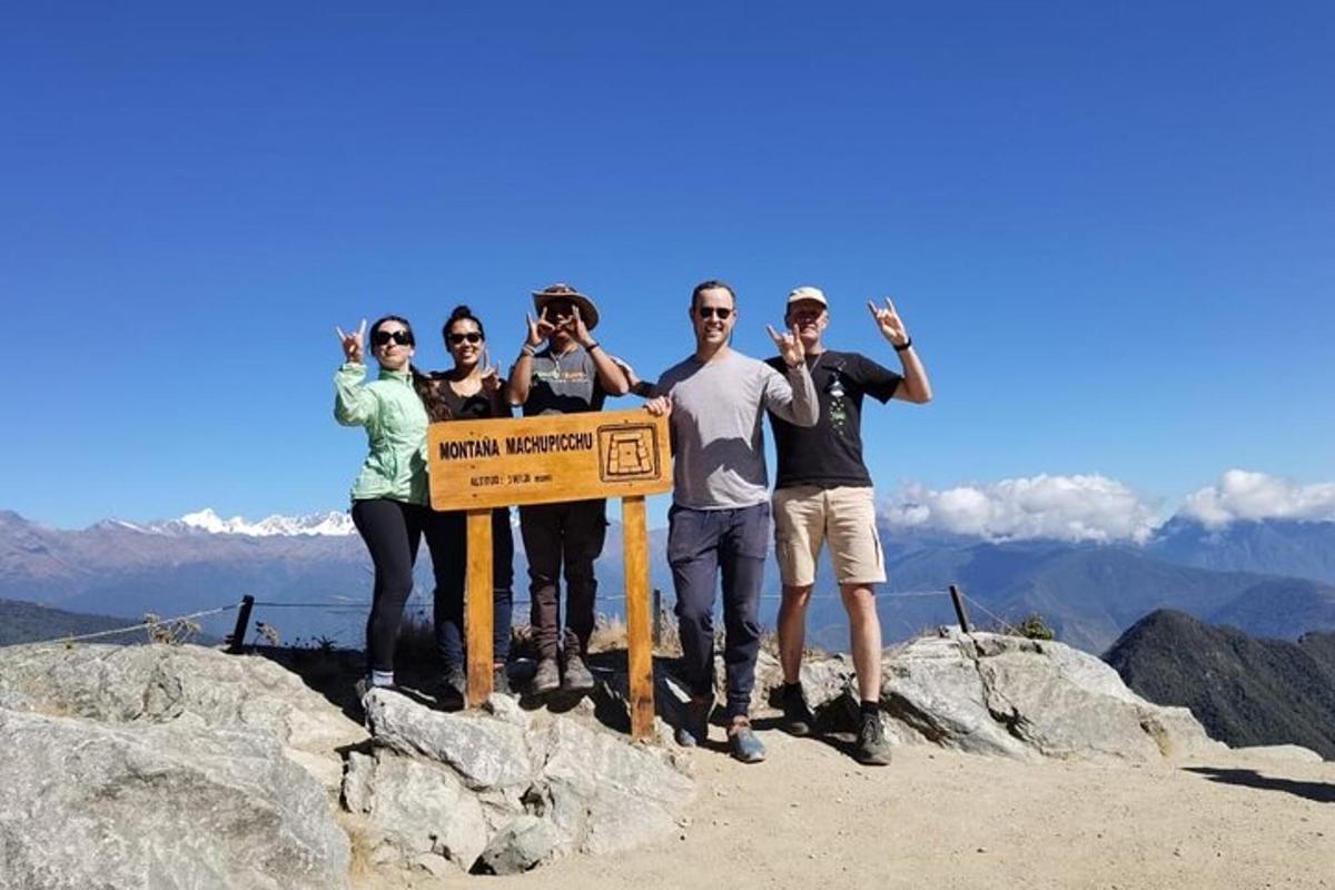 sekumpulan orang berdiri mengelilingi papan tanda di atas gunung