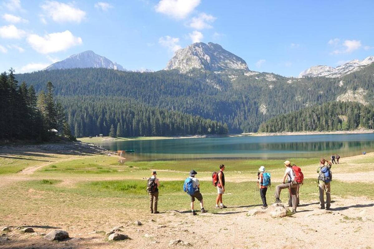 un grup de persones dretes en un turó prop d'un llac