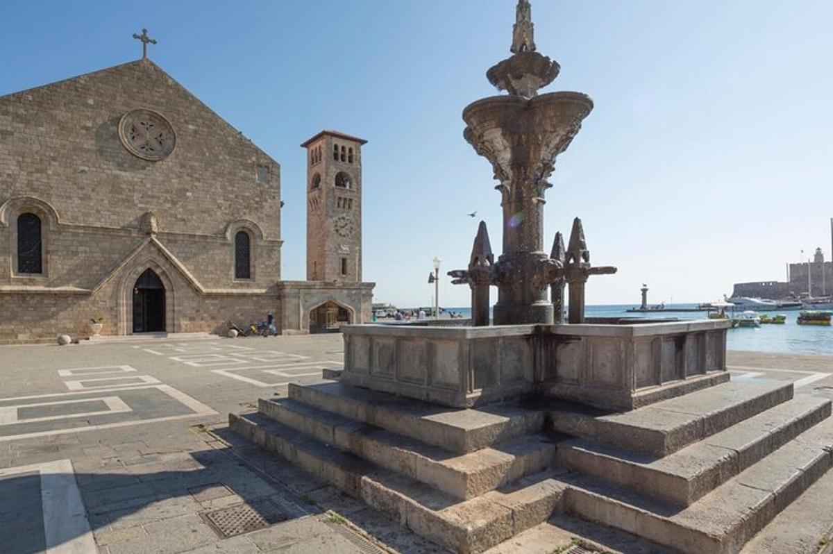 una chiesa con una fontana di fronte a una torre dell'orologio
