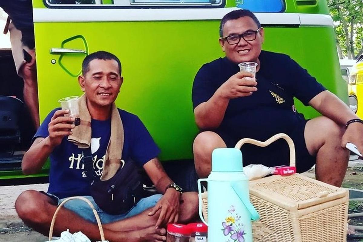 hai người đàn ông ngồi cạnh nhau cầm đồ uống