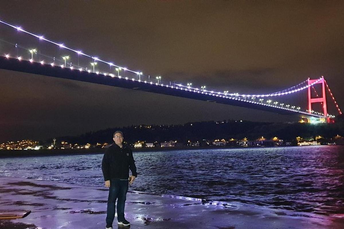 a man standing in front of a bridge at night