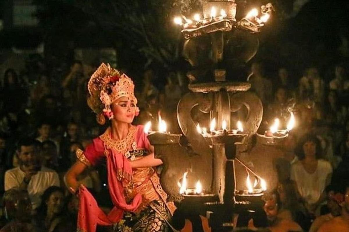 seorang wanita berjalan di depan kerumunan dengan lilin