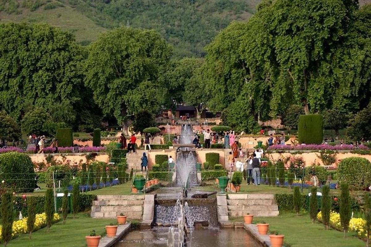 a fountain in a garden with people standing around it