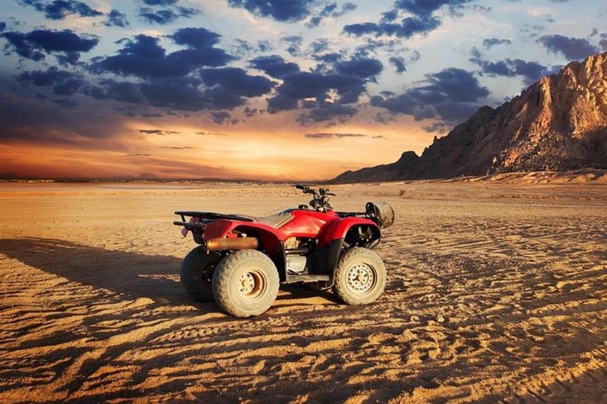 a red atv parked on the beach at sunset