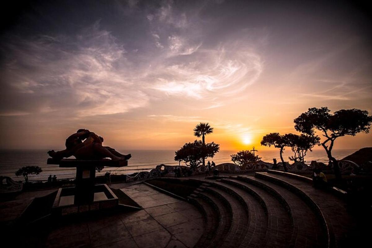 un tramonto con una statua di fronte all'oceano