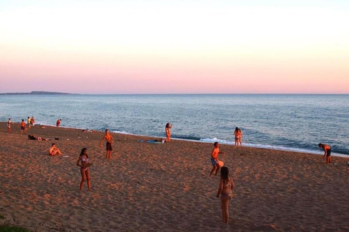 un grup de persones a la platja a la posta de sol