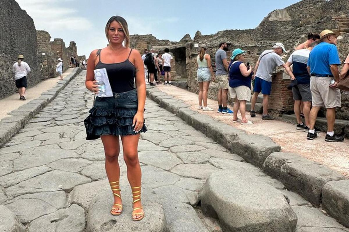 kona stendur á götunni við rústirnar