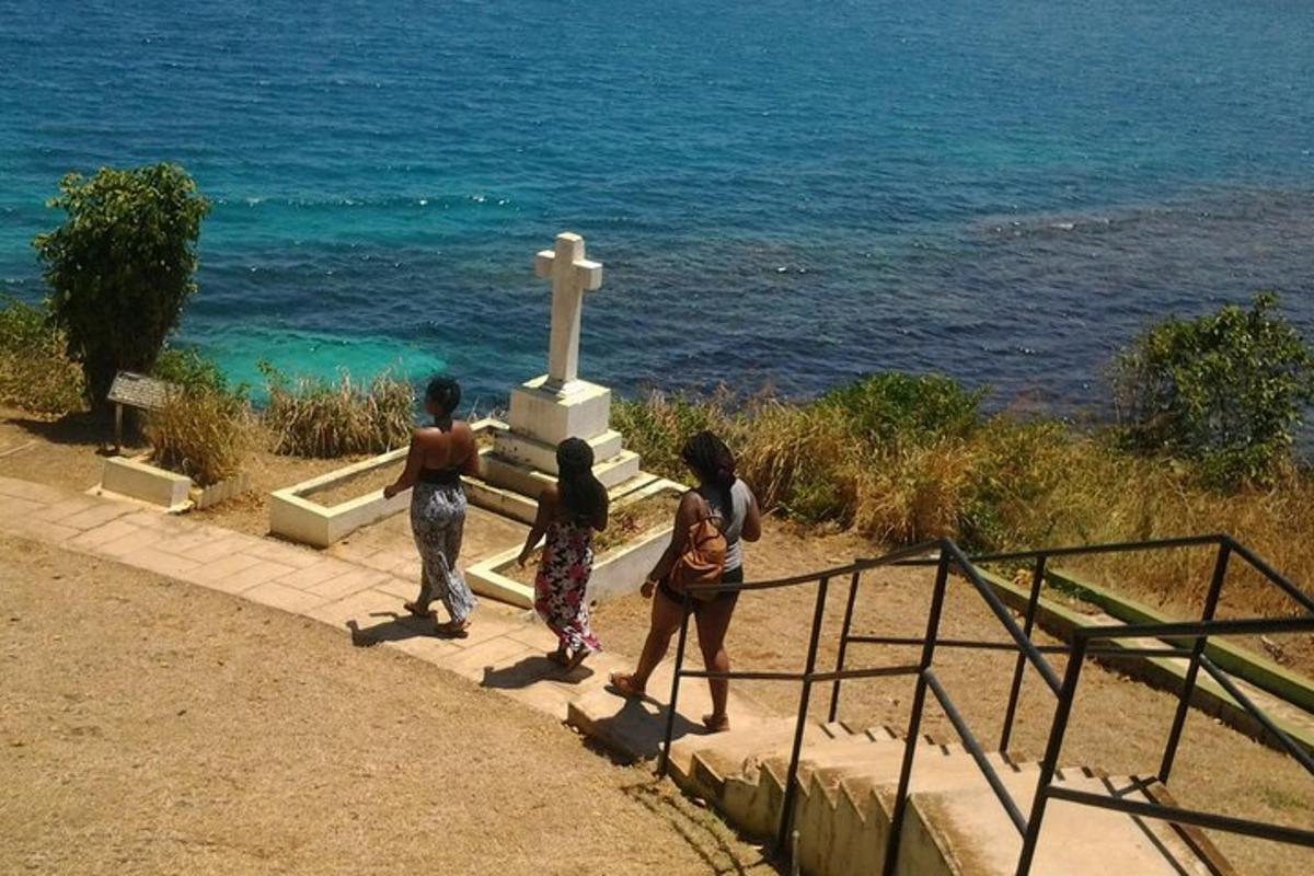 a group of people standing near a cross at the ocean