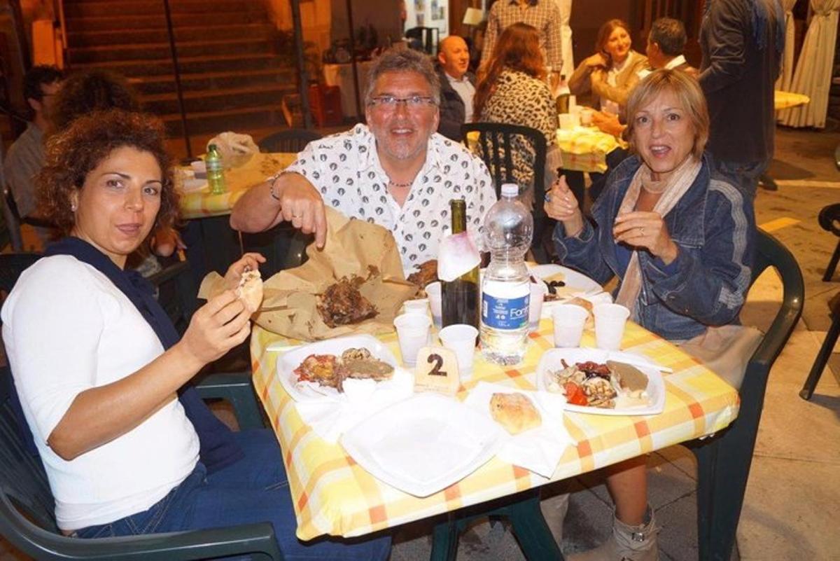 μια ομάδα ανθρώπων που κάθονται σε ένα τραπέζι τρώγοντας φαγητό