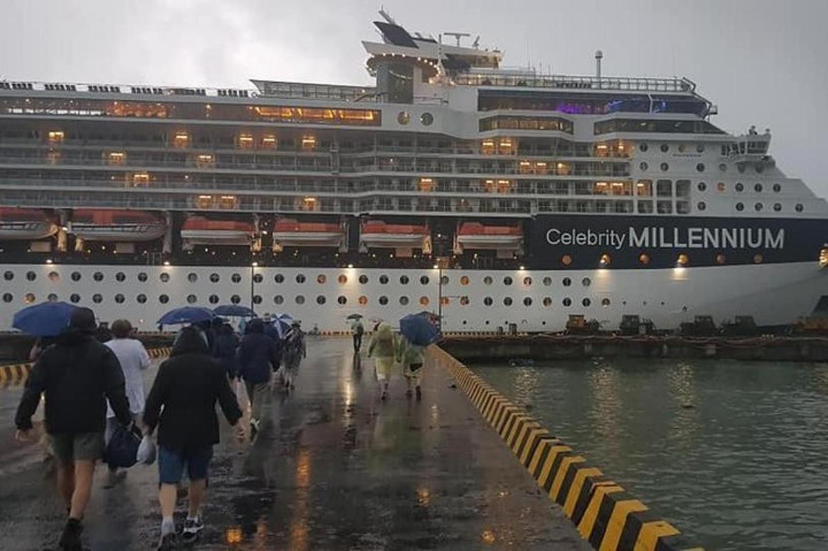 Ένα κρουαζιερόπλοιο είναι αγκυροβολημένο στη βροχή με ανθρώπους με ομπρέλες