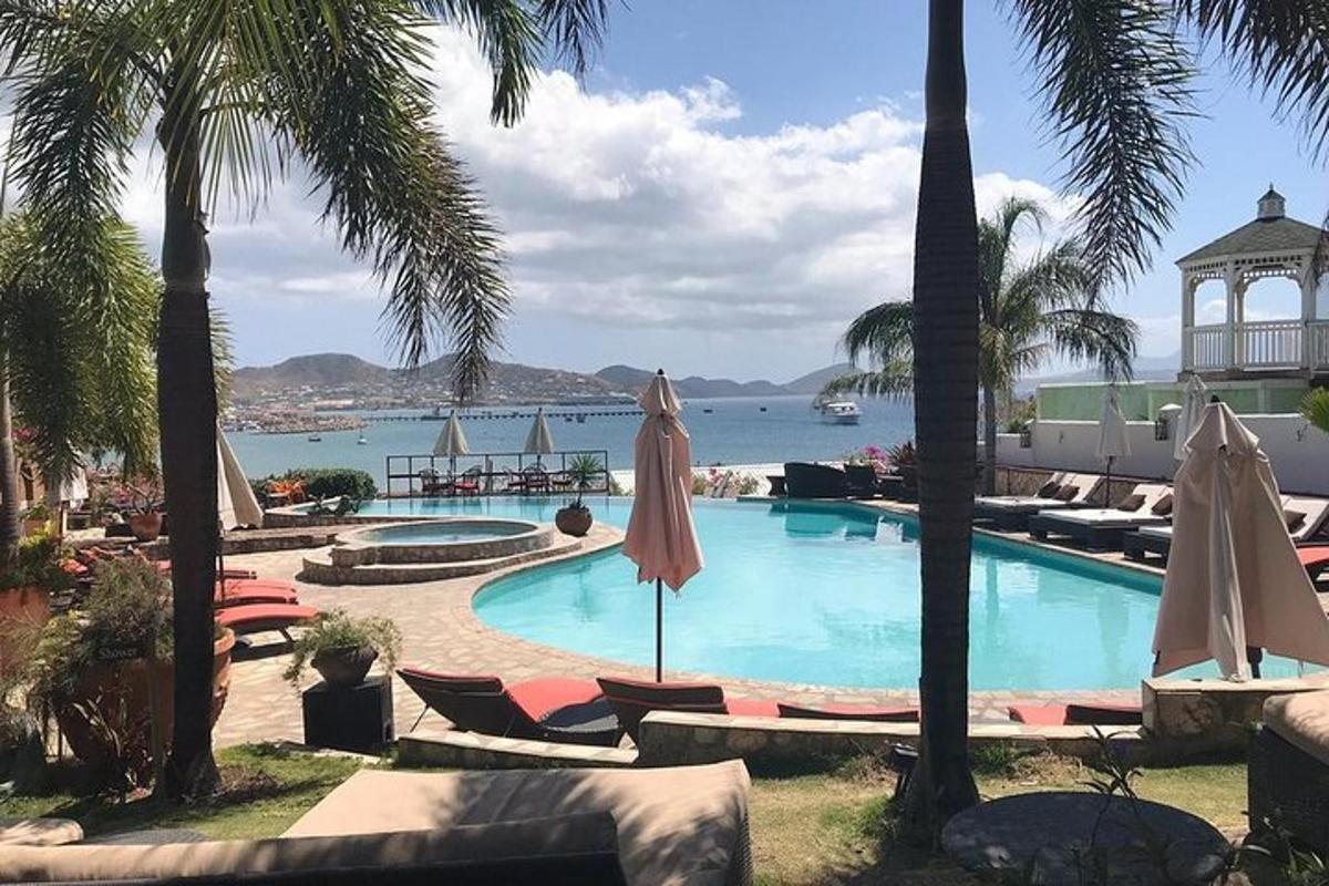 a swimming pool with chairs and umbrellas next to the ocean