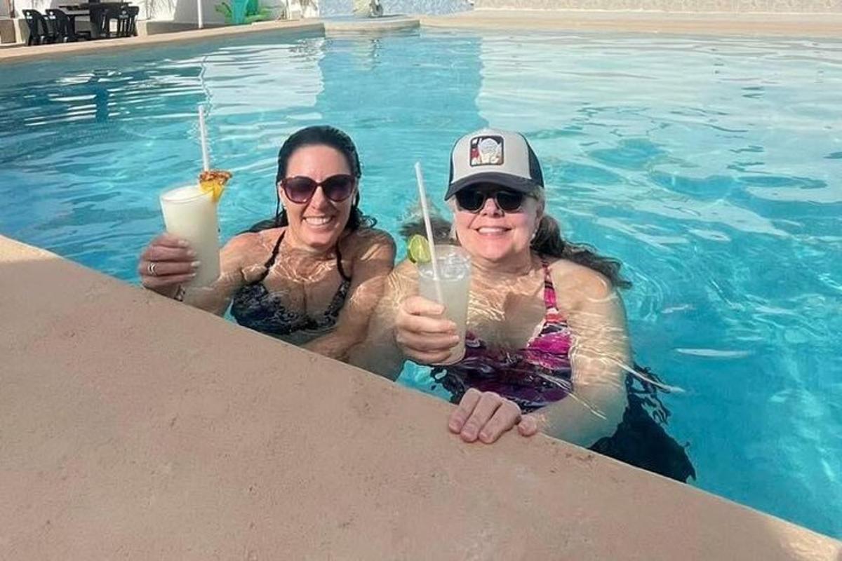 two women holding drinks in a swimming pool
