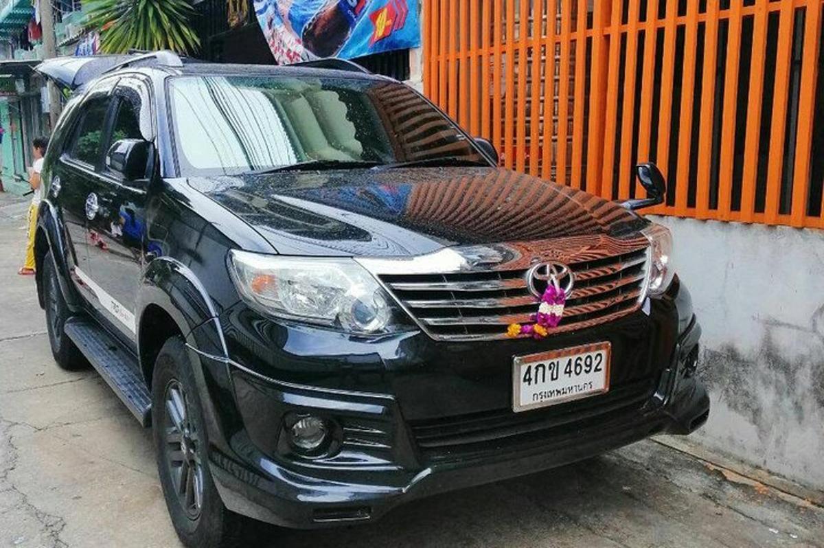 một chiếc xe màu đen đậu cạnh hàng rào