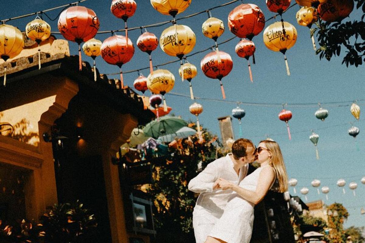 una sposa e uno sposo che si baciano sotto un mazzo di lanterne di carta