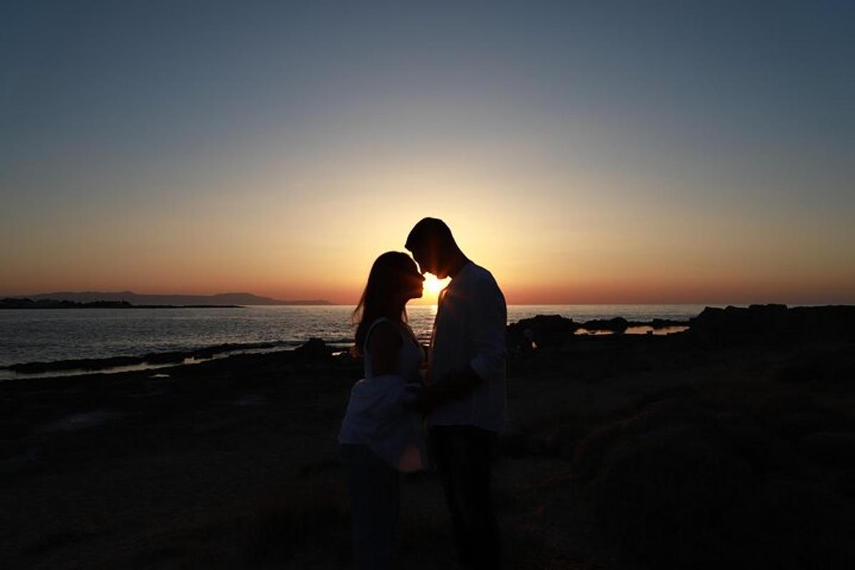 un uomo e una donna in piedi sulla spiaggia al tramonto
