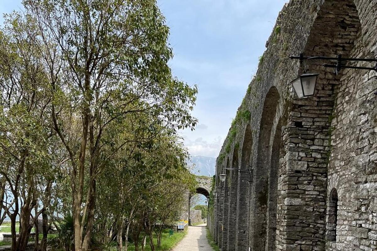 an old stone wall with trees on the side
