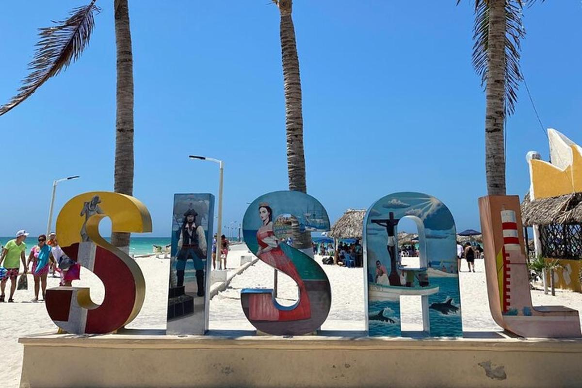 Un cartel frente a una playa con palmeras.