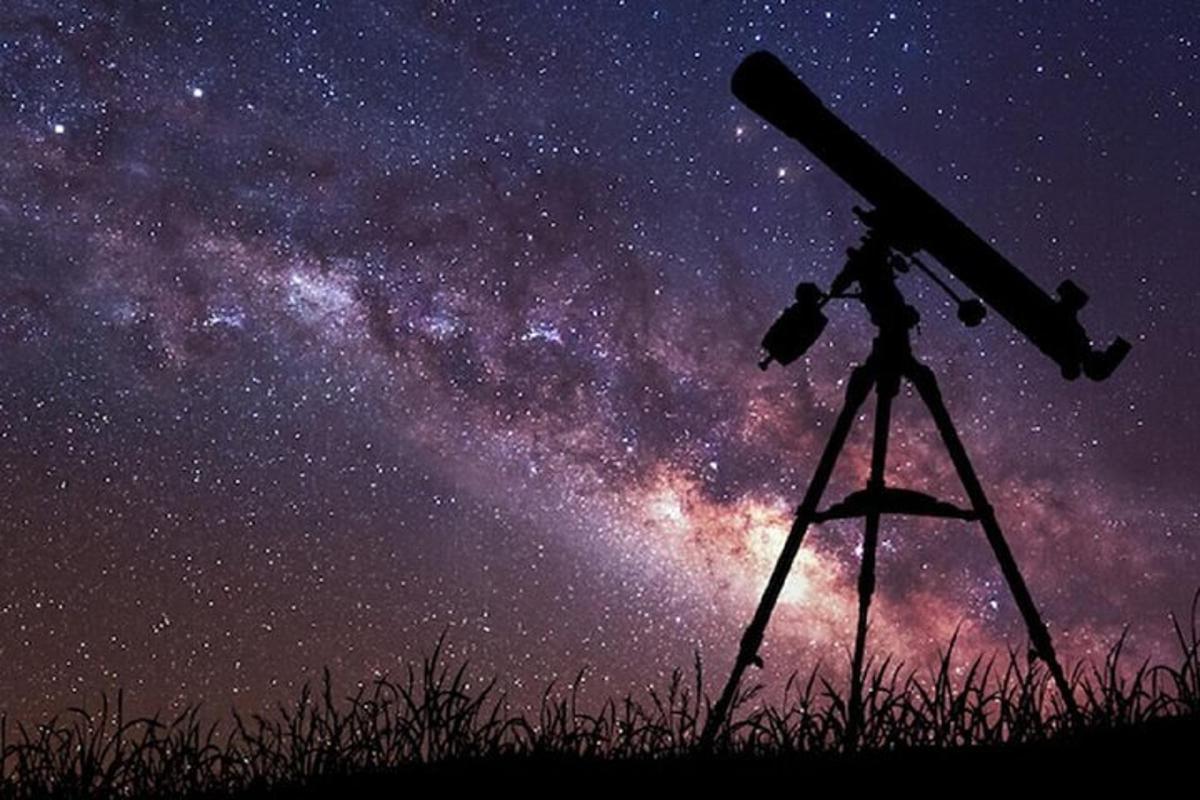 un telescopi sobre un trípode mirant la Via Làctia