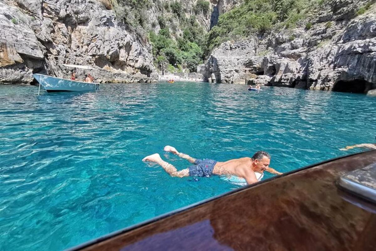moški leži v vodi poleg čolna