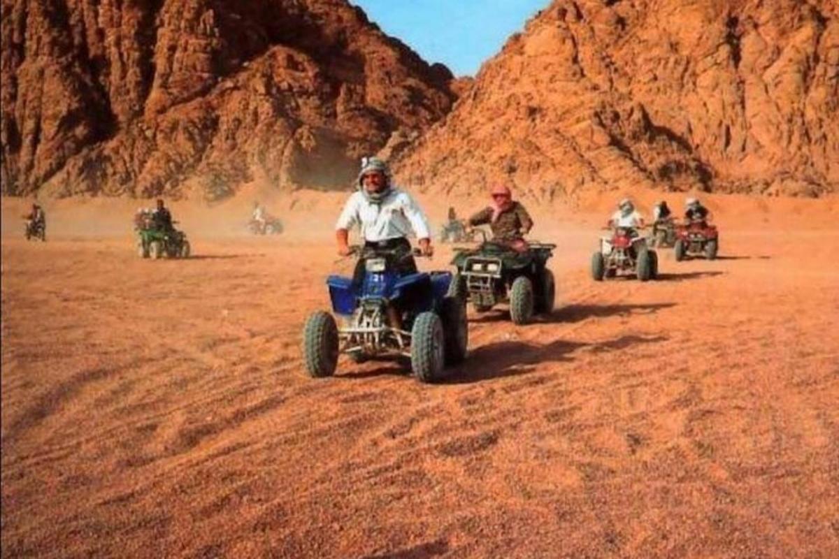 um grupo de pessoas andando de quadriciclo no deserto