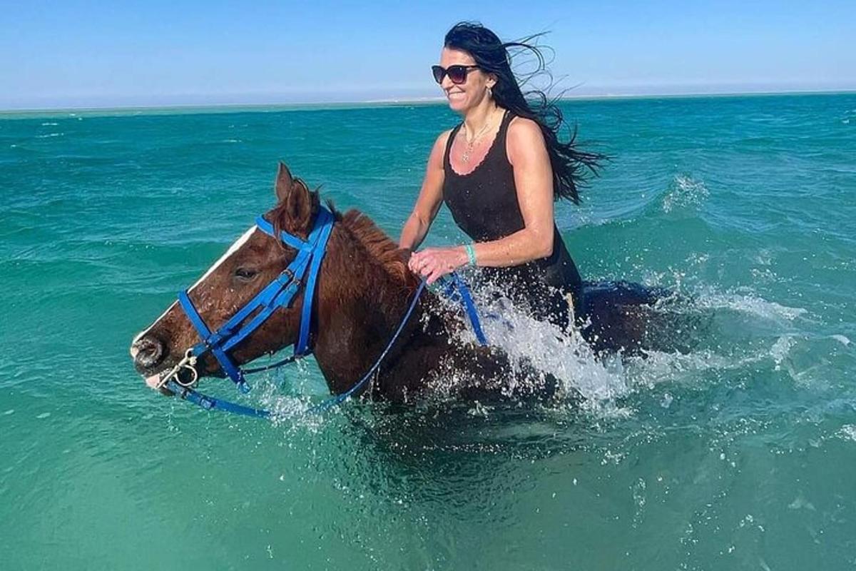 en kvinne som rir på en hest i havet