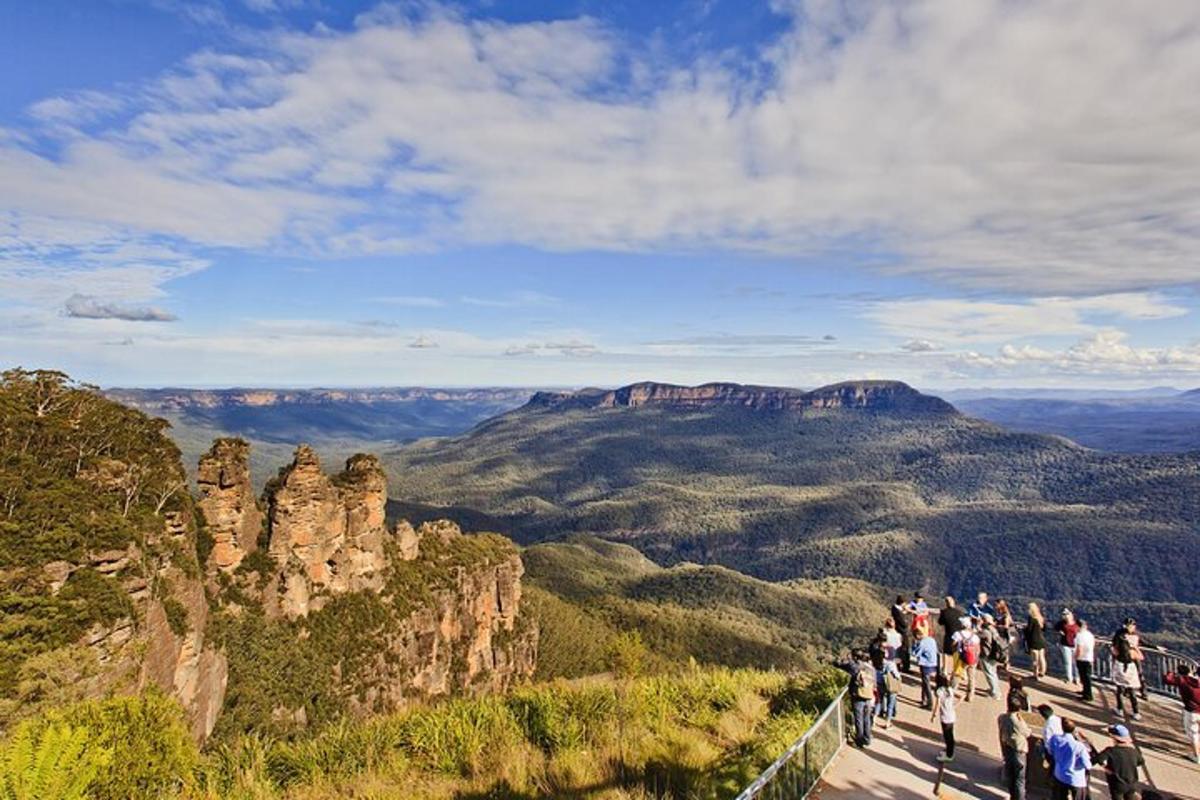 a group of people standing on the edge of a overlook of the blue mountains