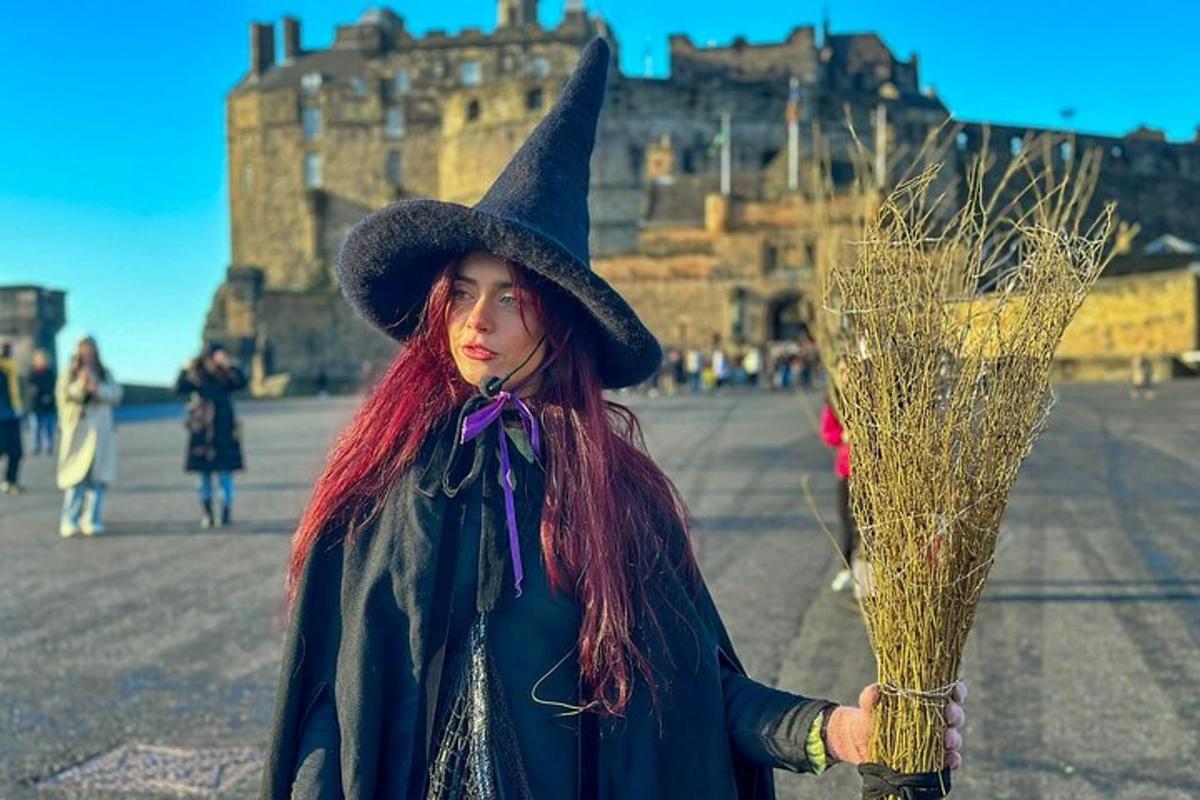 a woman in a witch hat holding a bunch of hay