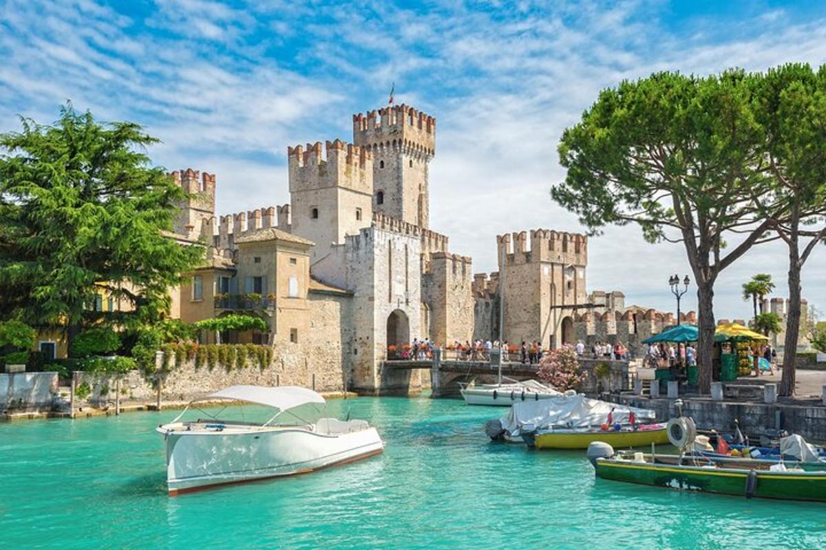 Un castillo con barcos en el agua frente a él.