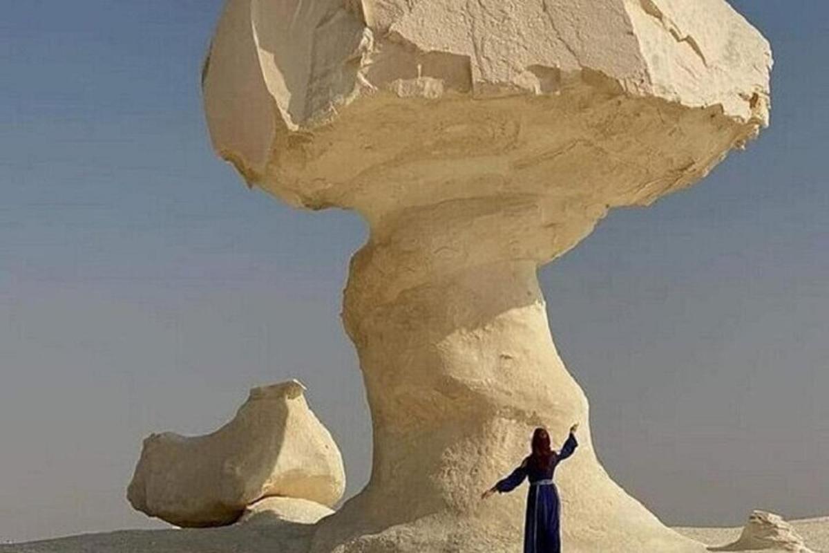 uma mulher parada em frente a uma formação rochosa