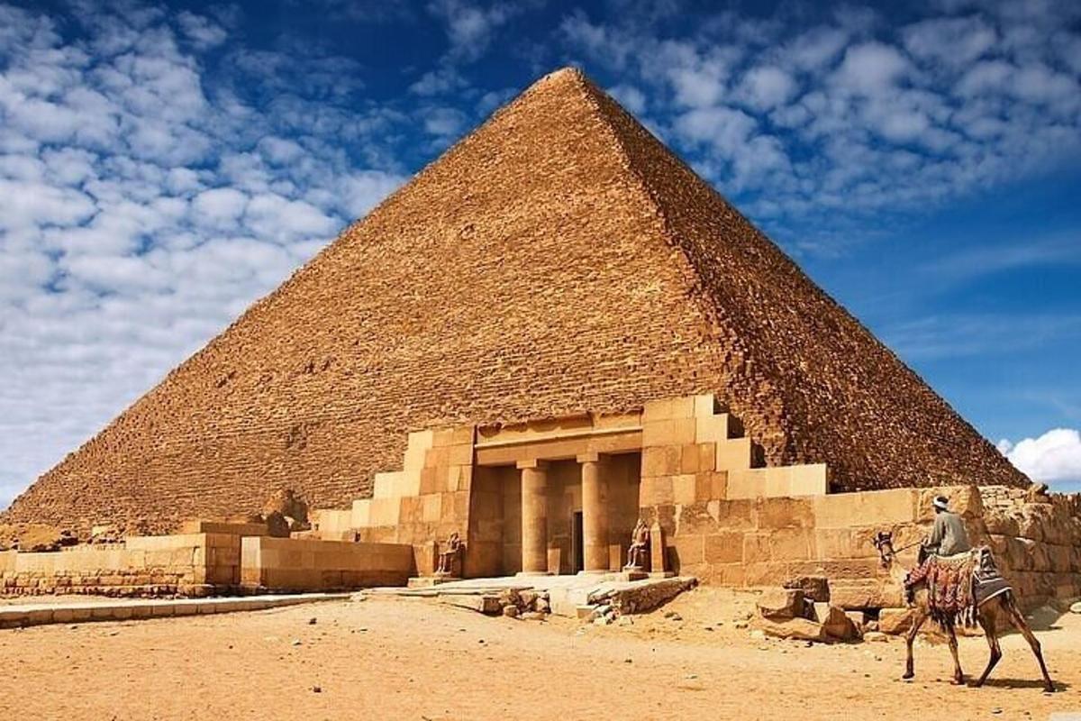 muž jazdiaci na ťave pred pyramídou