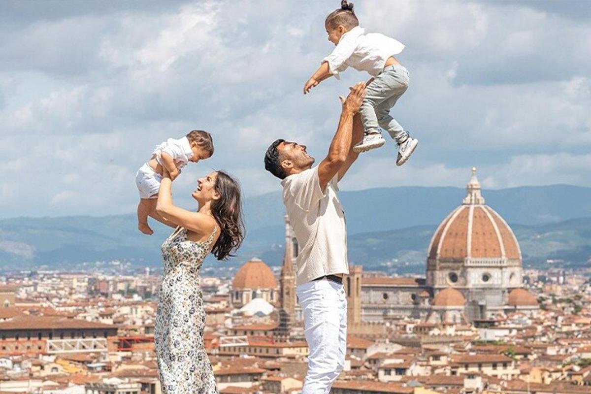 Un hombre y una mujer sosteniendo a un niño en la cima de una ciudad.