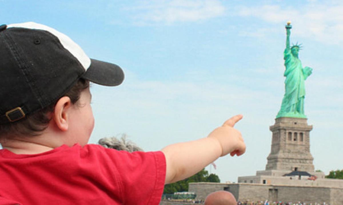 a young child pointing at the statue of liberty