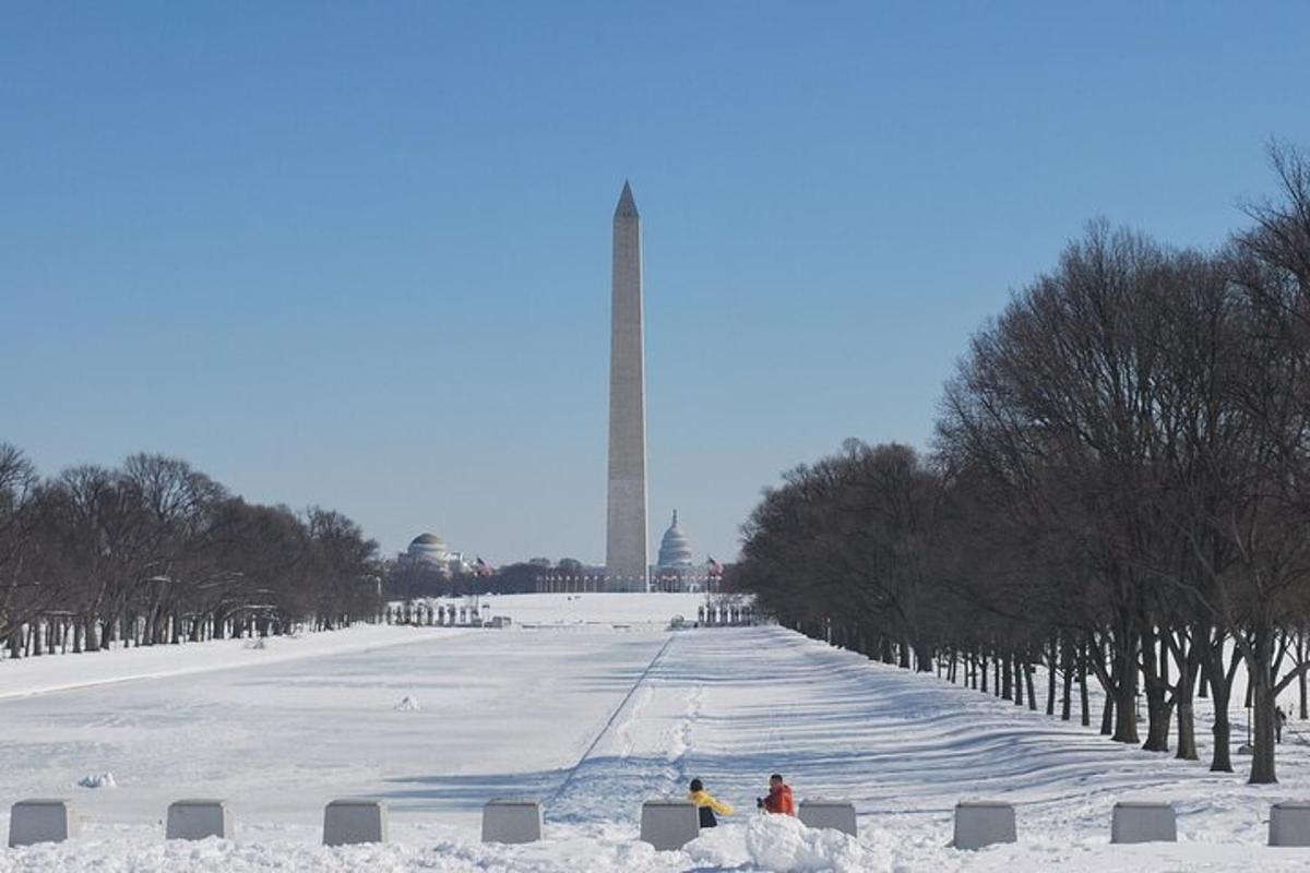 dua orang duduk di dalam salji di hadapan monumen washington