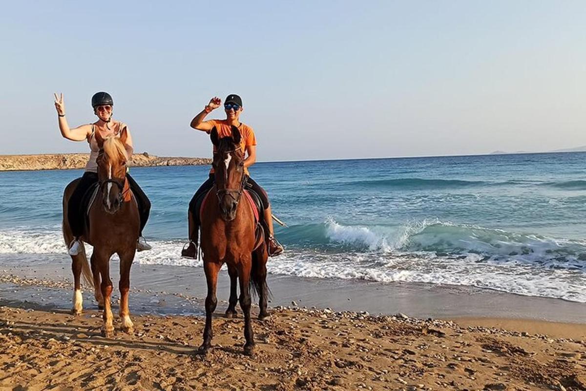dues persones muntant a cavall a la platja