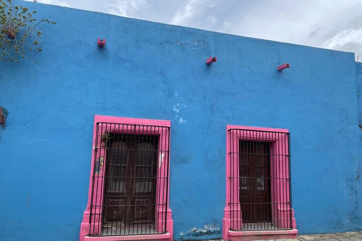 a blue building with three windows with pink