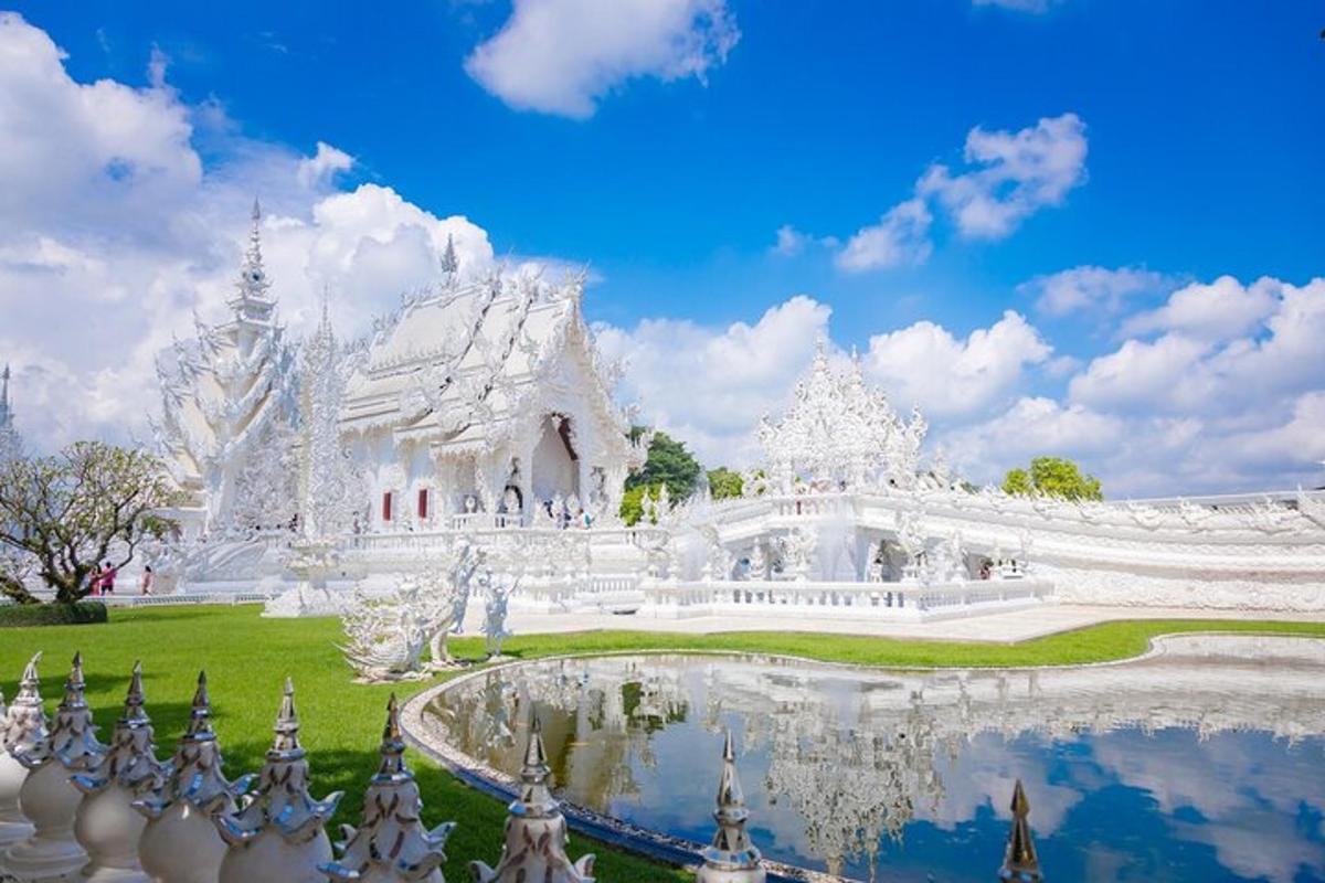 a white temple with a pond in front of it