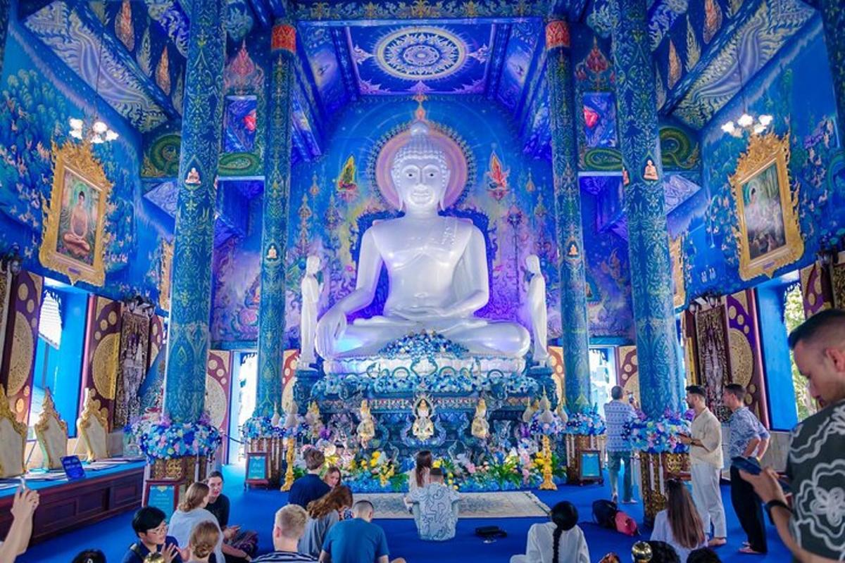 a crowd of people in a temple with a large buddha statue