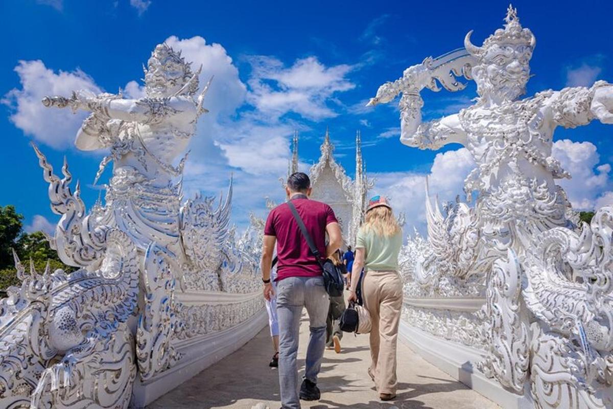 a man and woman walking across a bridge in front of a white temple