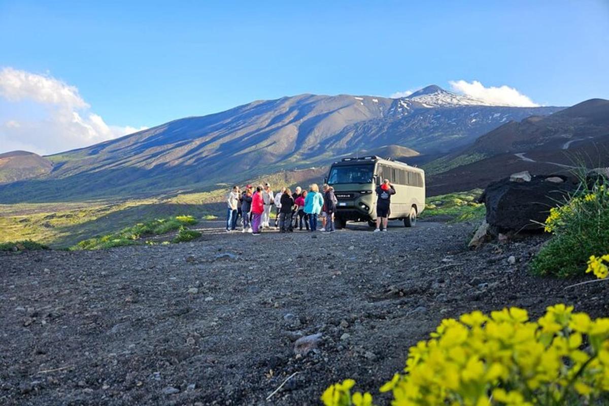 un gruppo di persone in piedi accanto a un autobus su una collina