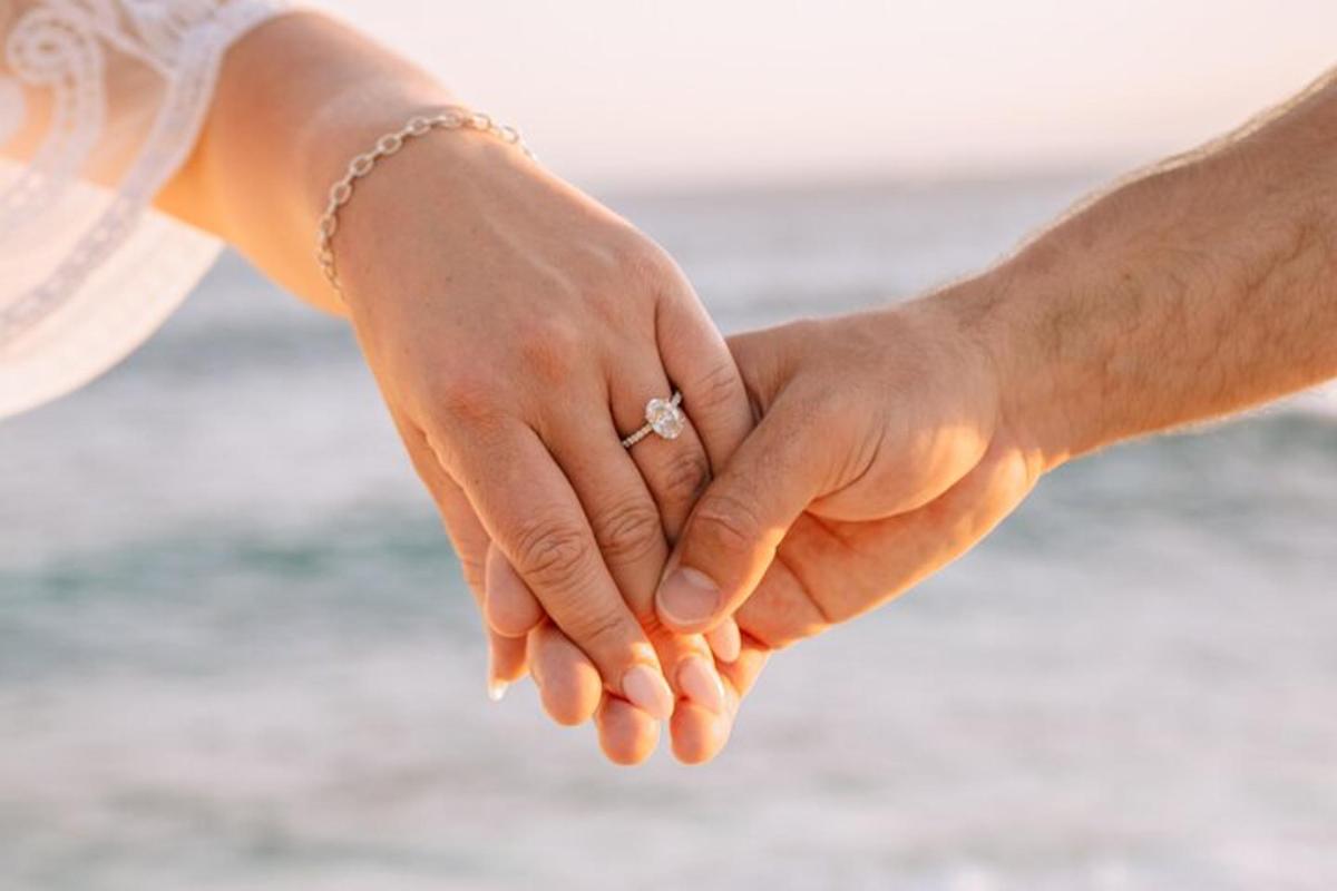 una sposa e uno sposo che si tengono per mano sulla spiaggia