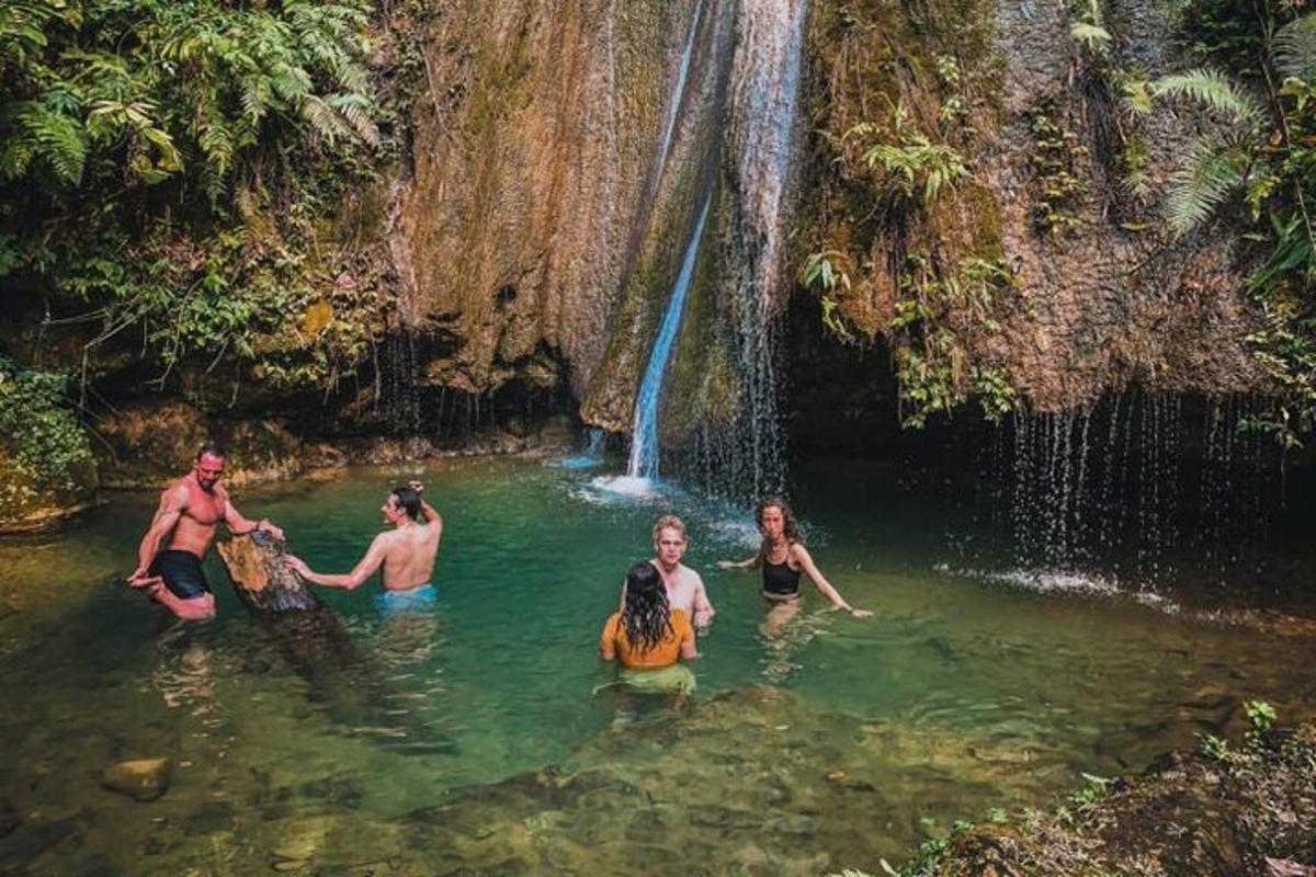 a group of people in the water near a waterfall