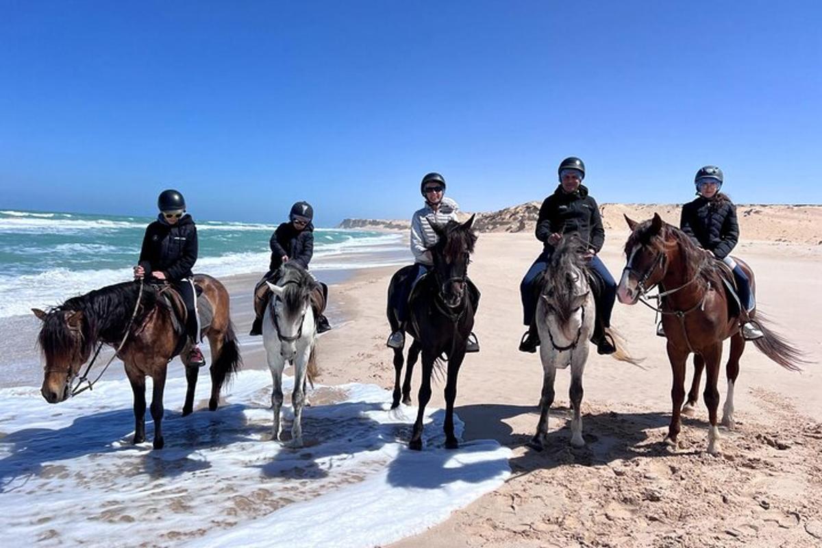 a group of people riding horses on the beach