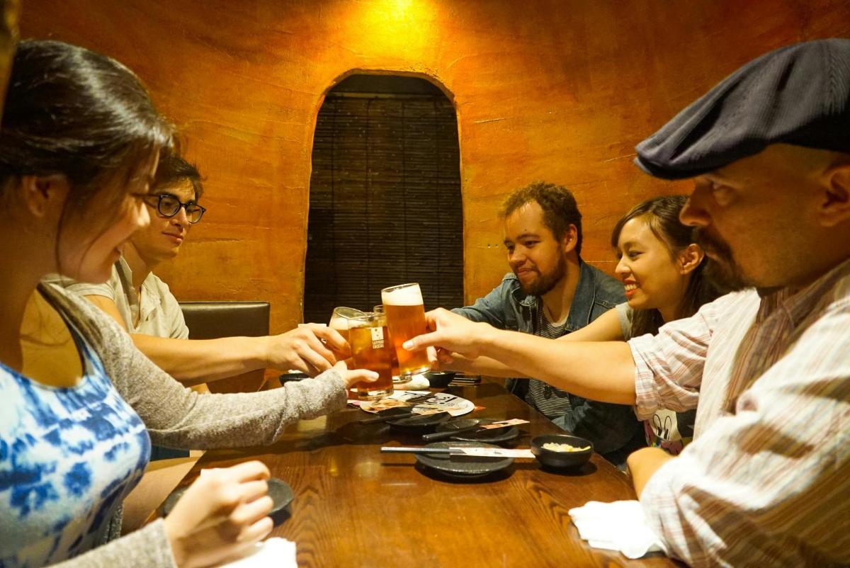 a group of people sitting around a table drinking beer